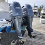 Two Yamaha 200 outboard motors mounted on a boat at a marina, with visible propellers and mounting brackets on a wooden dock.
