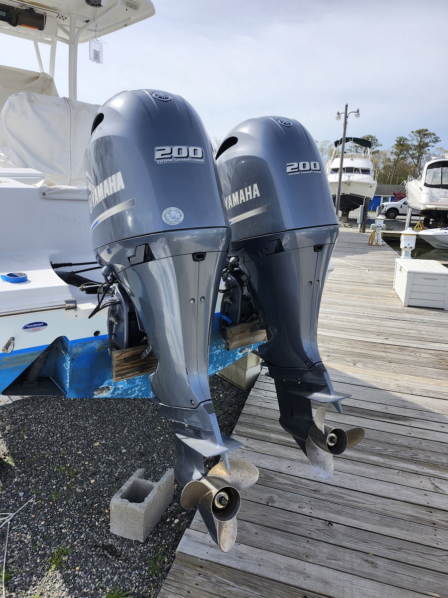 Two Yamaha 200 outboard motors mounted on a boat at a marina, with visible propellers and mounting brackets on a wooden dock.
