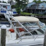 White motorboat docked at a pier with a beige canopy, orange life jackets on the seats, and a wooden seawall in the background.