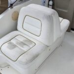 White boat cockpit seat with dirt stains and gold-trim cushions inside a cabin area.