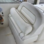 White captain's chair in a boat cockpit with a wooden steering wheel and dashboard controls nearby