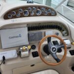 Boat helm interior showing a wooden steering wheel, gauge cluster, and Garmin navigation displays mounted on the dashboard.