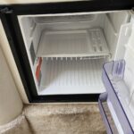 Compact freezer compartment in a small fridge, empty except for a purple ice cube tray on the door.