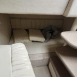 Cream/beige cabin seating area with cushions and a curved dining table, likely on a boat or RV.