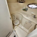 Compact airplane lavatory with beige interior, toilet, sink, and round porthole window.