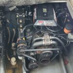 Boat engine compartment with a 5.7L MerCruiser EFI V8, belt drive, and rusted exhaust manifold visible.