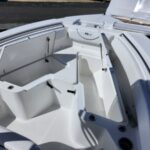 White boat interior with open storage hatch and seating compartments, showing clean epoxy-like surfaces and built-in gear storage.