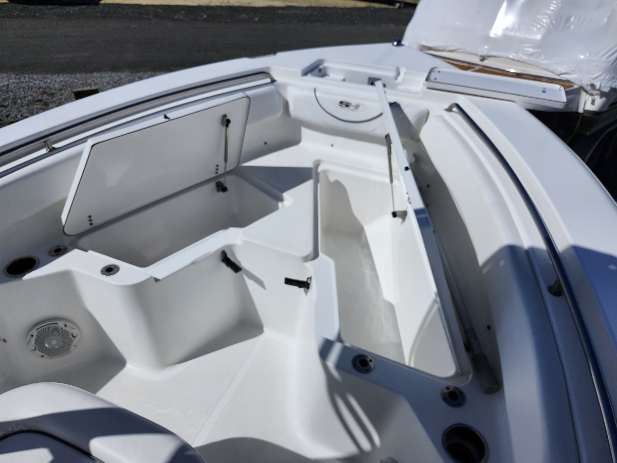 White boat interior with open storage hatch and seating compartments, showing clean epoxy-like surfaces and built-in gear storage.