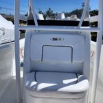 White captain's cockpit chair on a white boat, with padded backrest and seat cushion, under a T-top frame in bright outdoor light.