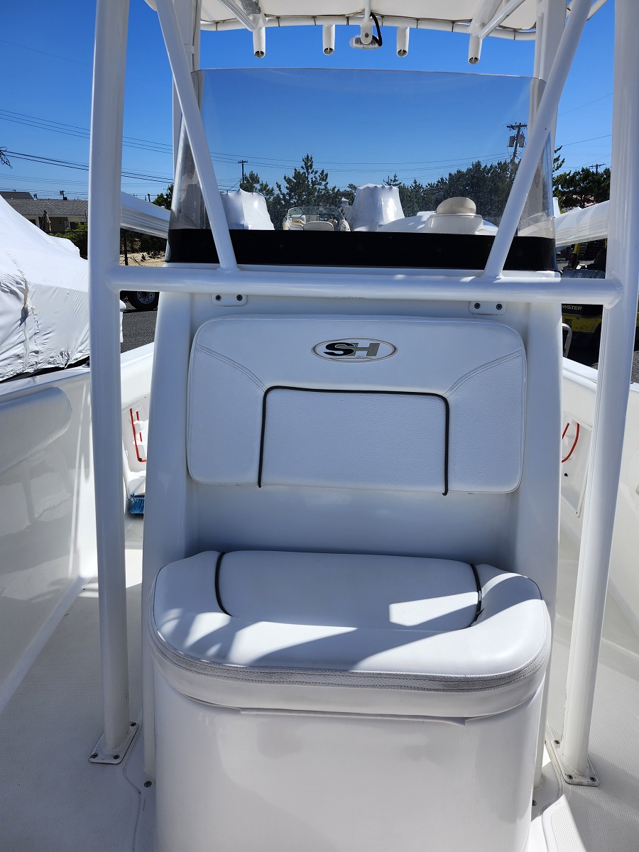 White captain's cockpit chair on a white boat, with padded backrest and seat cushion, under a T-top frame in bright outdoor light.