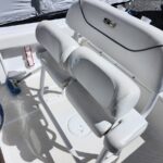White cushioned boat seats and console on a deck, with a blue brush and red lanyard nearby.