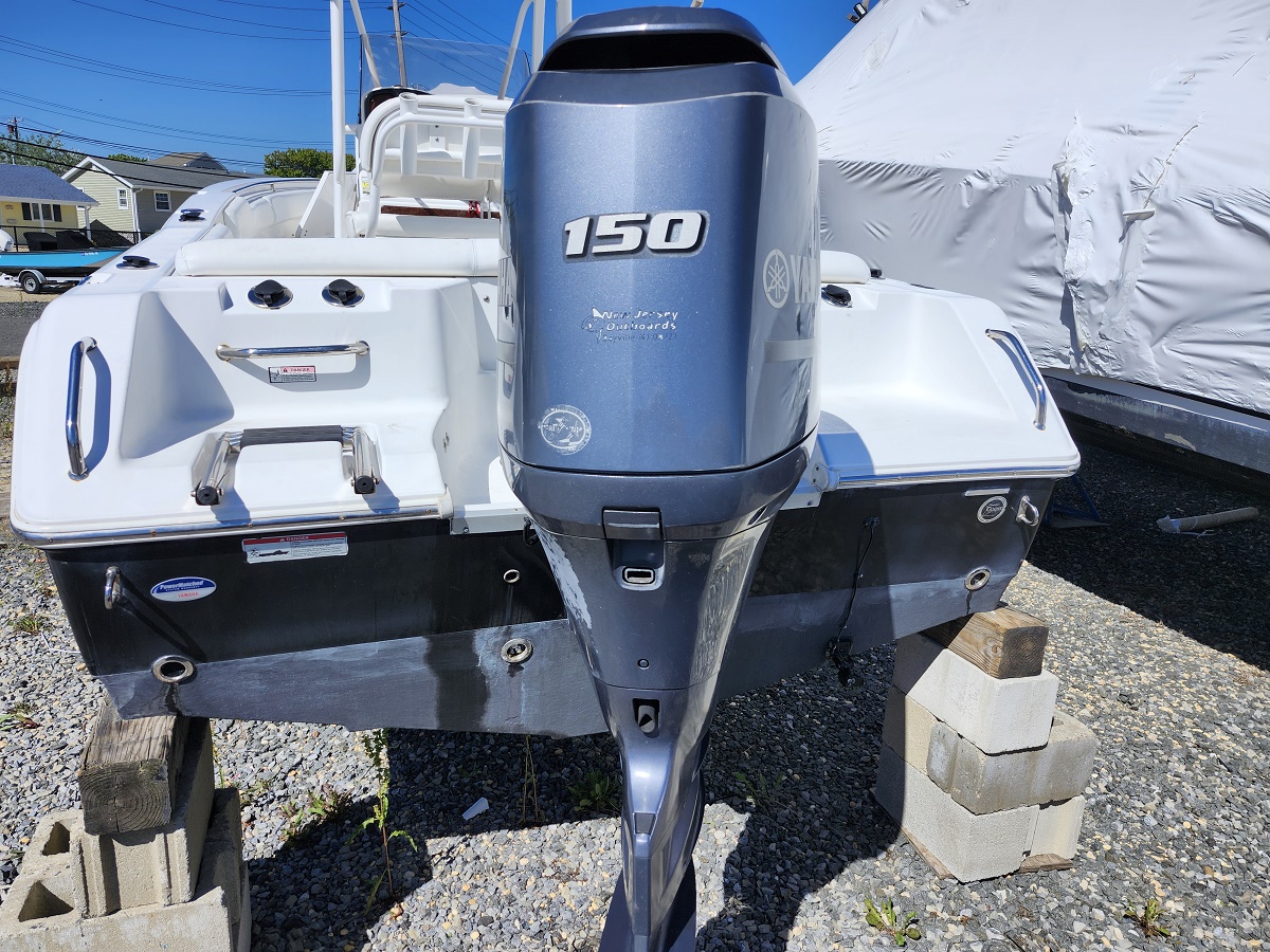Rear view of a sport boat on concrete blocks with a large blue Yamaha 150 outboard engine mounted on the stern