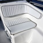 White boat seating with padded back and seat cushions, light gray piping, on a sunny deck.