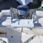 White boat cockpit with two cushioned bench seats, a small fold-down table with two cup holders, and a Yamaha 130 outboard motor at the rear.