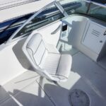 White captain's chair on a motorboat deck with curved windshield and nearby storage locker door