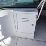 White storage locker door with vent slots integrated into a boat console near the windshield area.