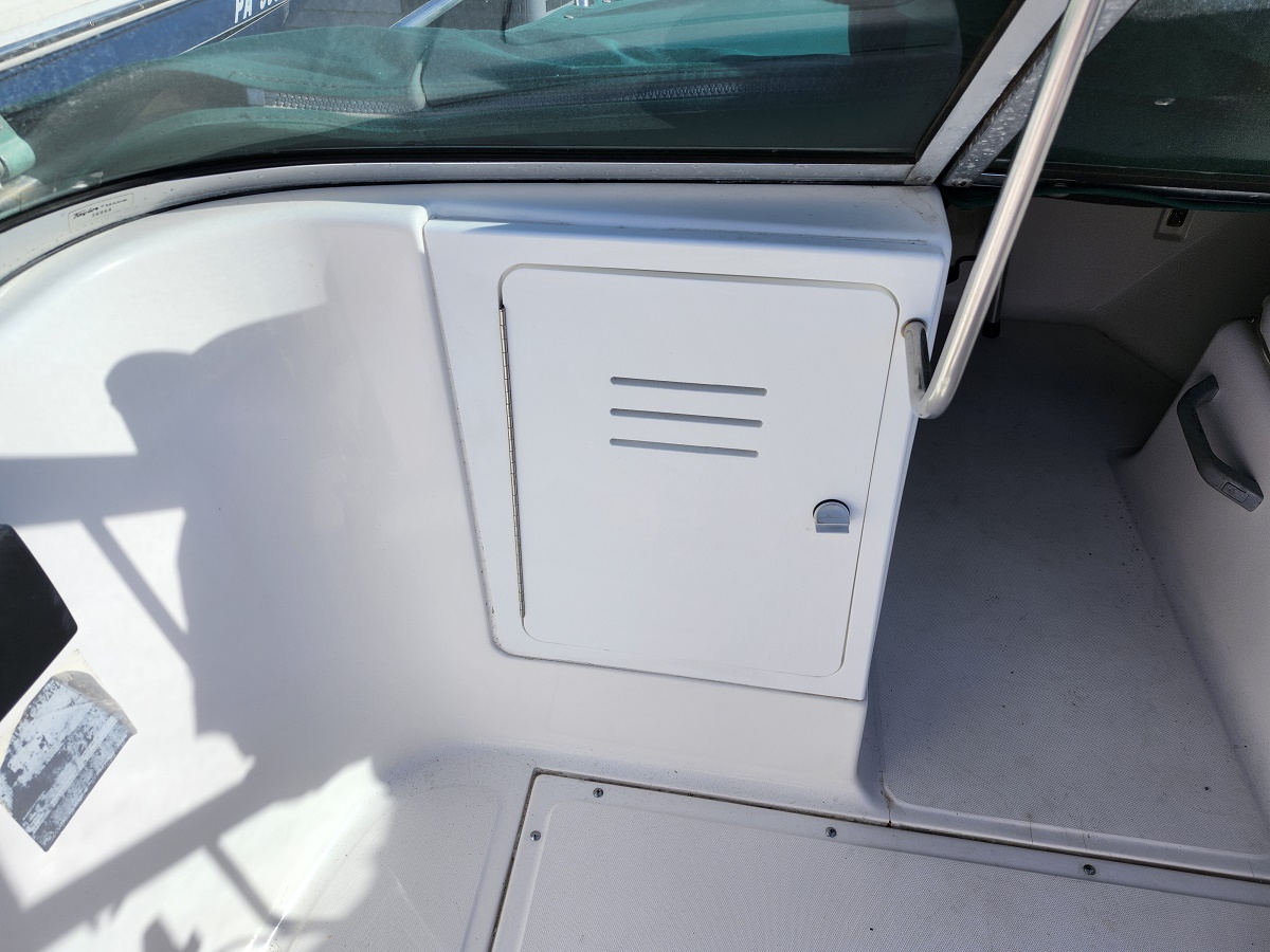 White storage locker door with vent slots integrated into a boat console near the windshield area.
