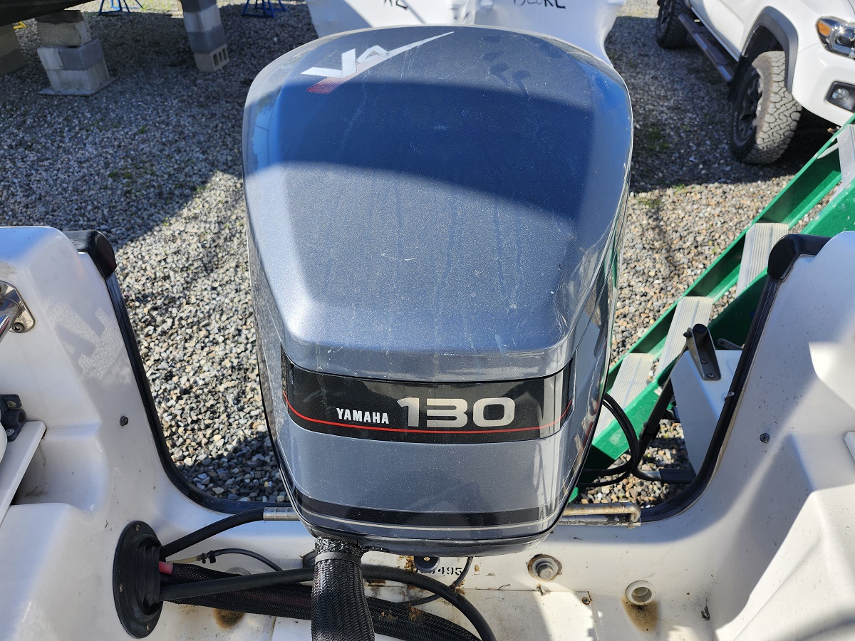 Close-up of a gray Yamaha 130 outboard motor mounted on the stern of a white boat, with a dusty cowling and visible cables.