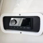 Marine stereo head unit embedded in a white panel with a black bezel; shows Fusion brand, control knob and playback buttons (power, menu, play/pause)