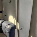 Beige vehicle interior with a padded vertical panel, blue armrest, and a circular cup holder opening on the panel.