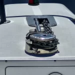 Anchor windlass with chain on the bow of a boat, chrome cleat and anchor chain ready for retrieval.