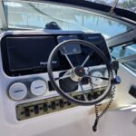 Boat helm with steering wheel and Raymarine displays overlooking calm marina.