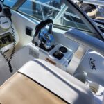 Speedboat cockpit with chrome throttle control, captain's seat, and instrument panel on a white dash.
