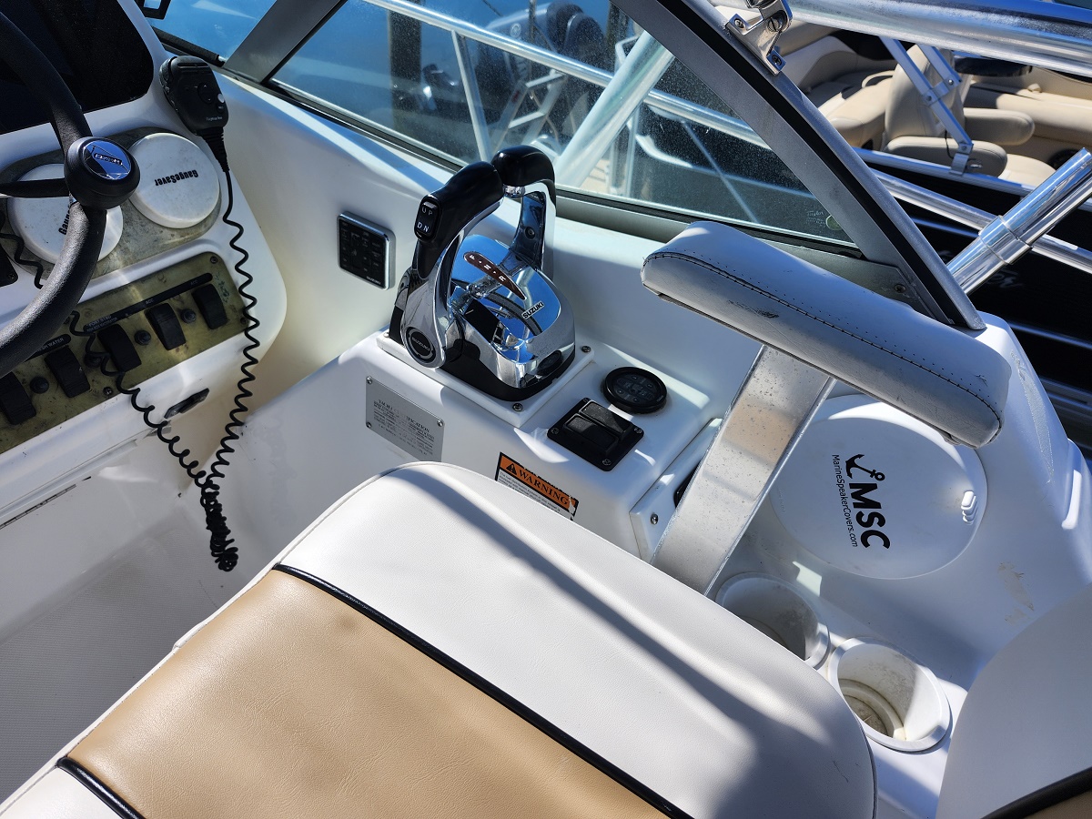 Speedboat cockpit with chrome throttle control, captain's seat, and instrument panel on a white dash.