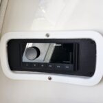 Fusion marine stereo head unit mounted in a white recessed panel, with a large round volume knob and playback buttons