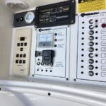 Marine electrical panel with 120 V AC controls, showing AC main, refrigerator, microwave, and cabin outlets.