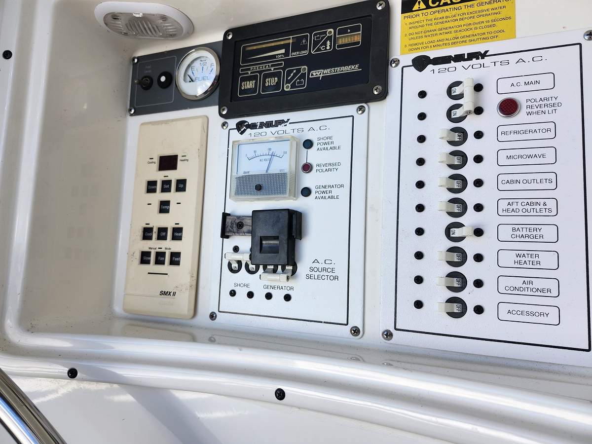 Marine electrical panel with 120 V AC controls, showing AC main, refrigerator, microwave, and cabin outlets.