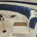 Curved white boat seating with blue back cushions and tan stripe cushions on a white deck.