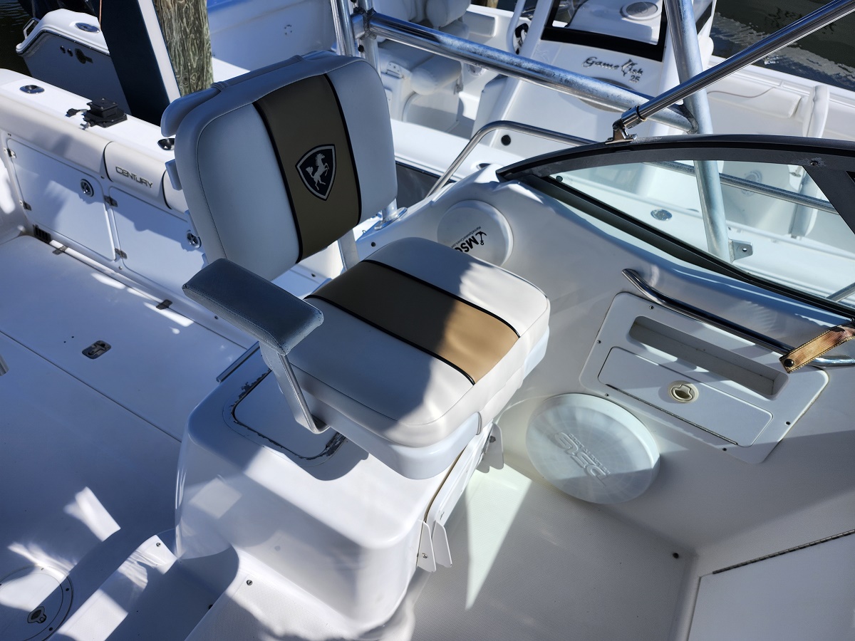 White captain chair with tan stripe in a boat cockpit, logo on backrest, mounted on a pedestal near the helm.