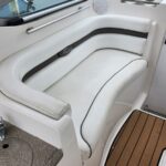 White curved boat cockpit seating with backrest and black accent trim, adjacent to a cup holder and chrome rail.