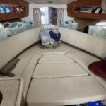 Cozy boat cabin with cream U-shaped leather seating, storage baskets along the walls, and folded blankets/pillows on top.