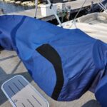 Blue boat cover over a boat on a marina dock with other boats nearby in the background.