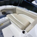White motorboat cockpit with tan cushioned U-shaped seating and a built-in cup holder by the water's edge at a marina