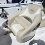 Beige and white captain's chair on a boat deck, mounted beside the console with a red lanyard nearby.
