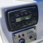 Boat radio console with Infinity stereo and control buttons mounted on a white boat panel, Bluetooth enabled display visible beside climate dust.