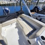 Open cockpit of a white boat with tan cushioned seating, dock and another boat visible in the marina.