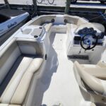 NauticStar center-console boat cockpit with beige cushioned seating and steering wheel, dock mooring visible outside.