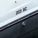 Car badge on a white car reading '203 SE' near the door seam (informational)