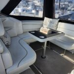 White leather boat seating around a rectangular table with a small wooden centerpiece; marina visible through the large windows.