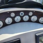 Boat dashboard with multiple round gauges on a wood-panel background, partially covered by a black canvas cover.