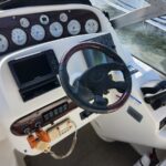 Boat helm with steering wheel, gauges, and Garmin navigation screen on white console.