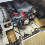 View of a Volvo Penta inboard marine engine in a boat's engine compartment, with belts, pulleys, and hoses surrounding a red engine block on a white bilge.