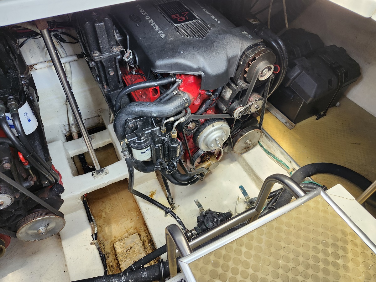 View of a Volvo Penta inboard marine engine in a boat's engine compartment, with belts, pulleys, and hoses surrounding a red engine block on a white bilge.