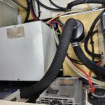 Electrical cabinet with thick black cables and a flexible conduit inside a utility panel.
