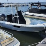 White Key West motorboat docked at a marina beside a covered speedboat and calm water.