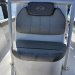 Gray boat chair with a cushioned backrest and headrest labeled 'KW' on a white boat interior, water in the background